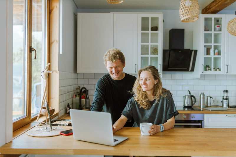 A man and a woman looking at their laptop, preparing for a video call